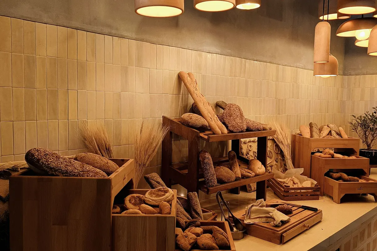 Houten rekken vol brood onder warme hanglampen in de winkel